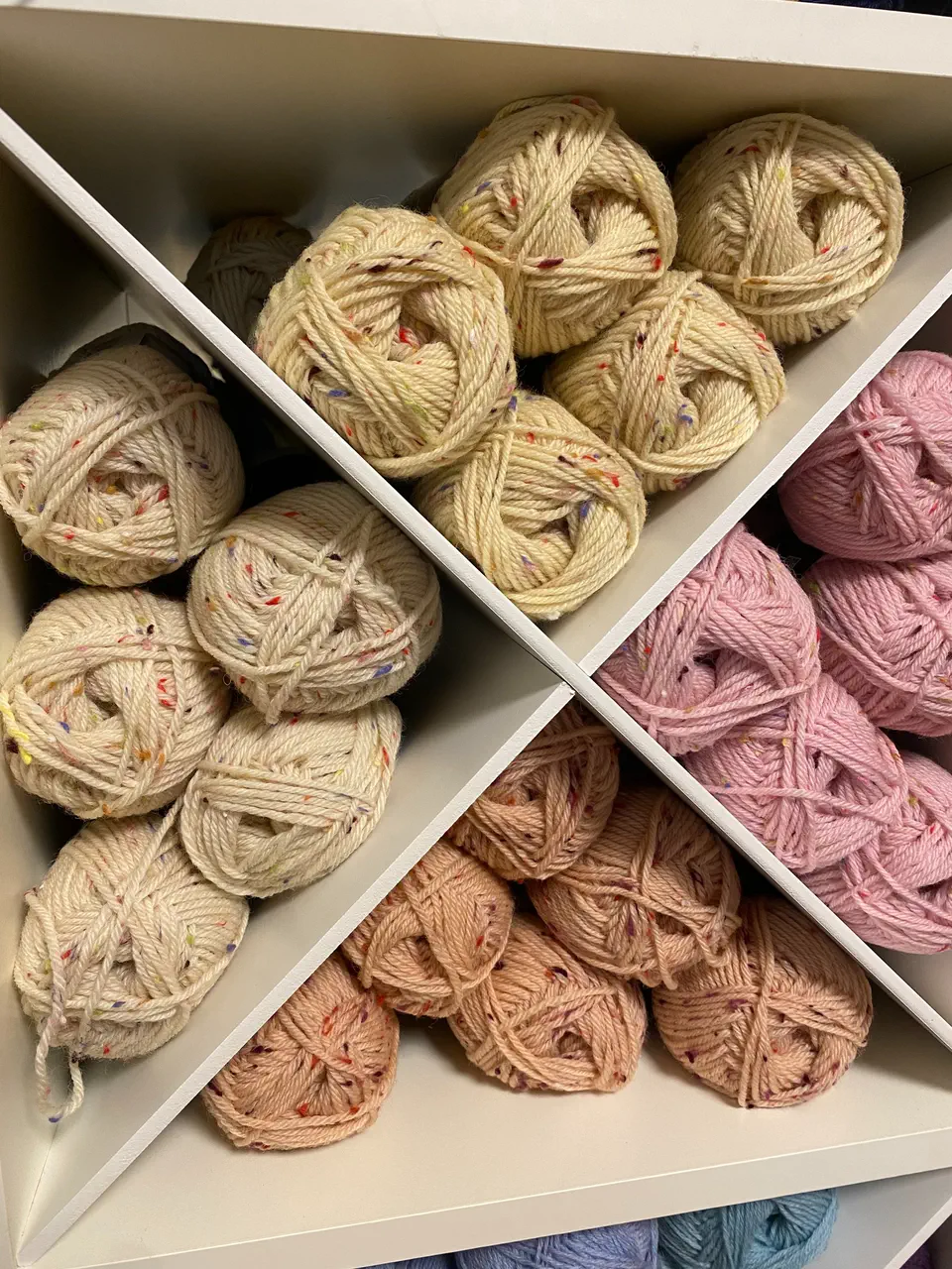 Nystan i naturvitt, beige och puderrosa sorterade i ett vitt kryssfack